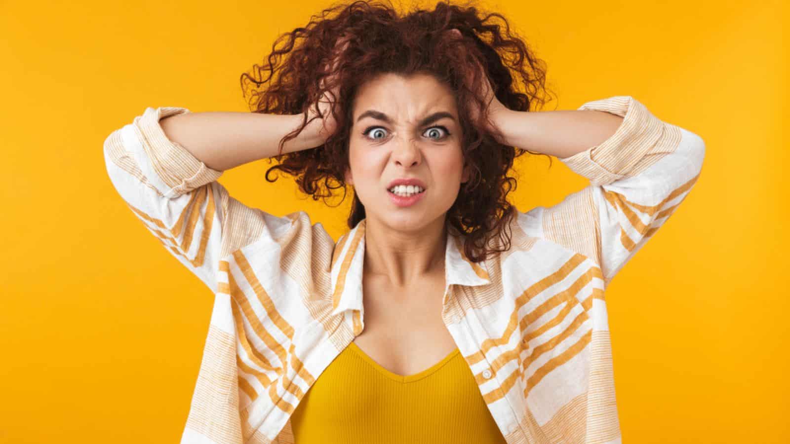 Annoyed frustrated aggressive woman with curly hair grabbing her head