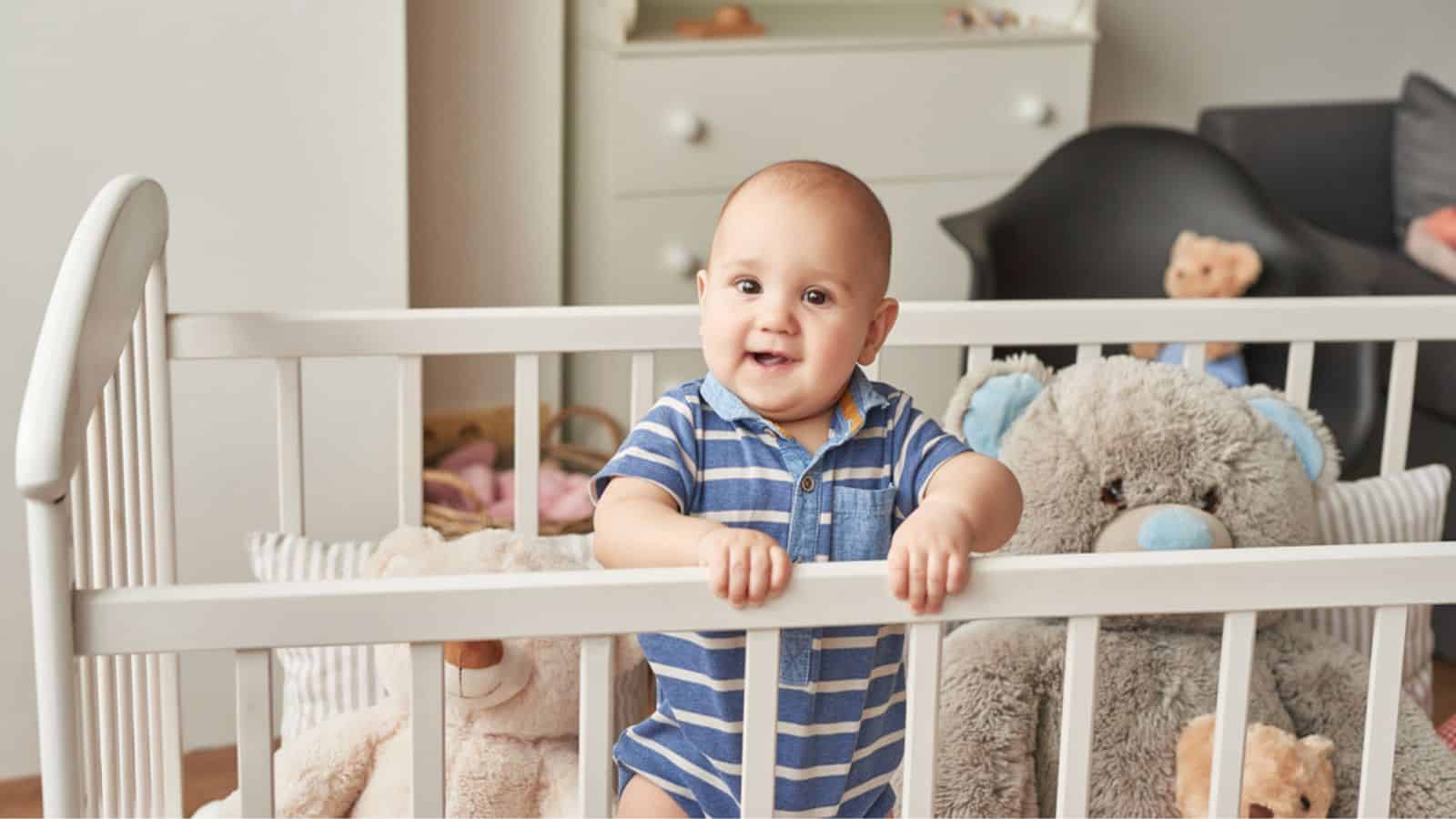Baby boy in a bed with toys in the children's room