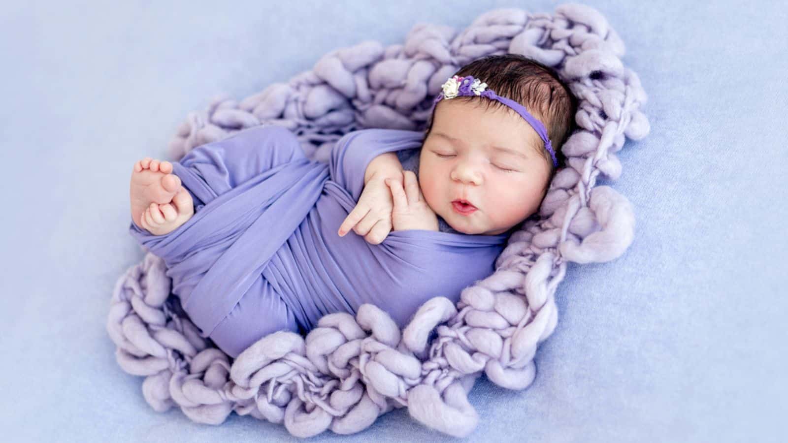 Cute newborn baby wrapped in purple blanked