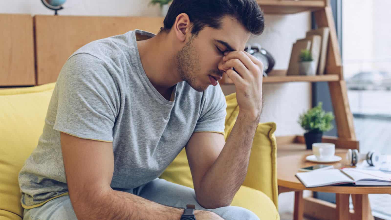 Exhausted and tired man sitting on sofa in living room