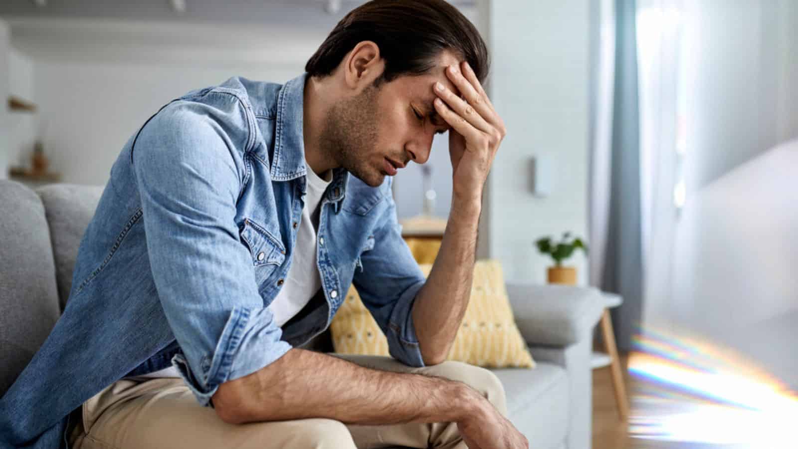 Frustrated man holding his head at home