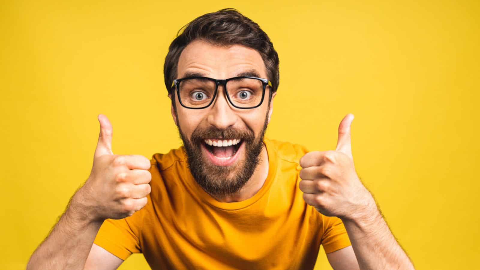 Happy young man thumbs up isolated in yellow