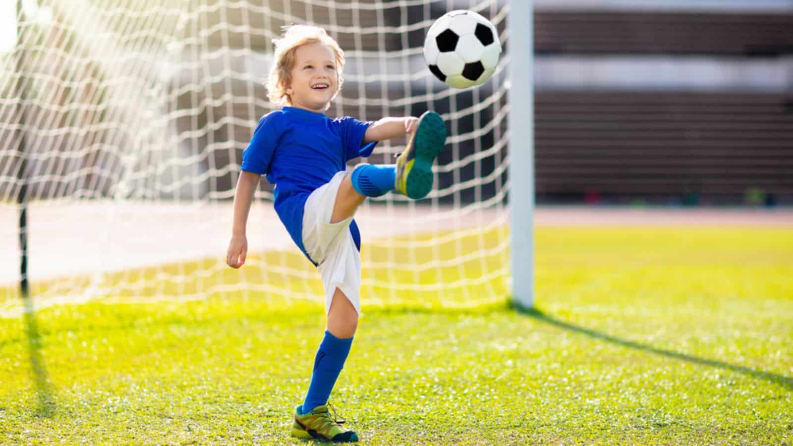 Kids play football on outdoor stadium field