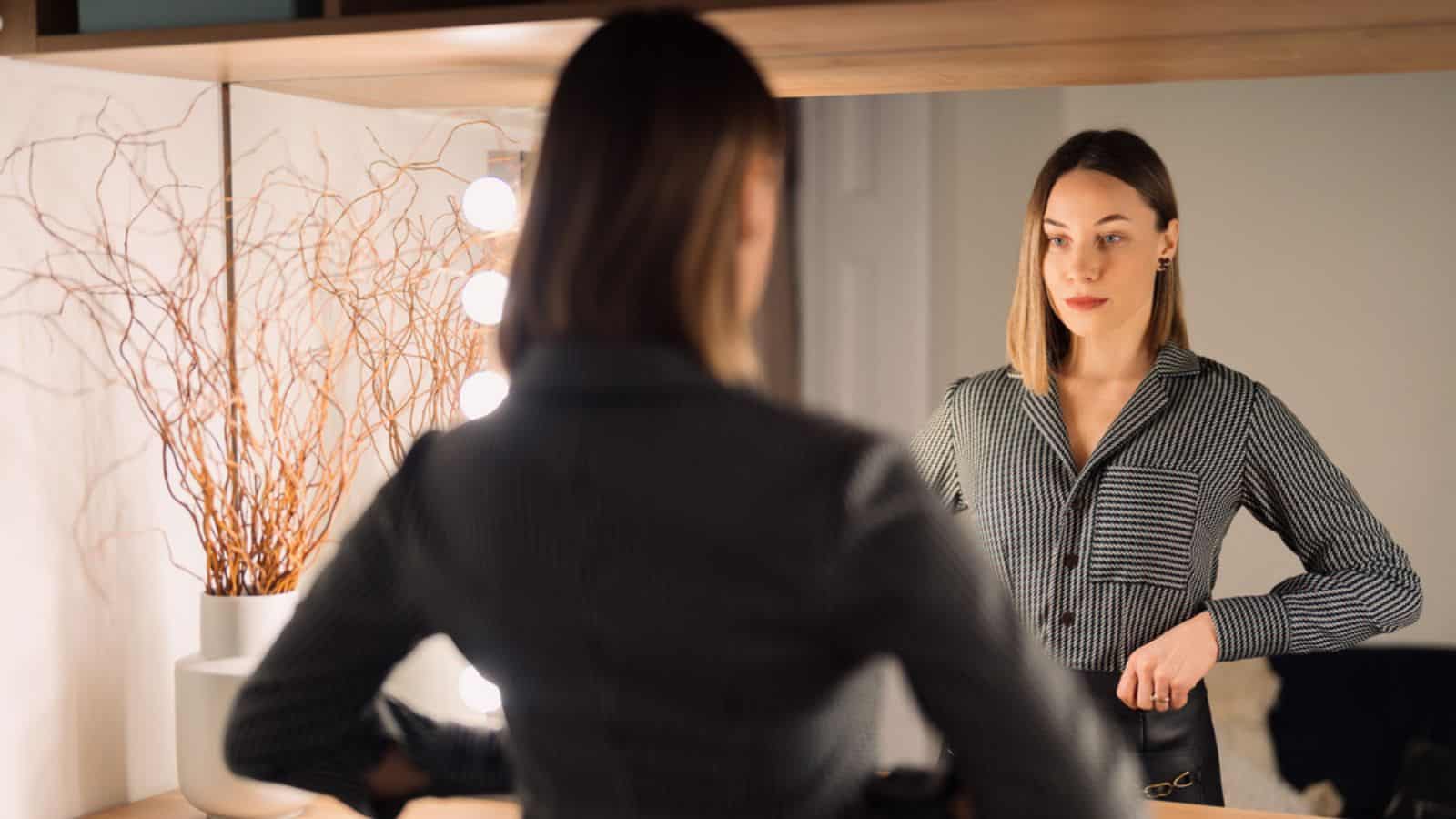 Lovely woman looking at her reflection in the mirror