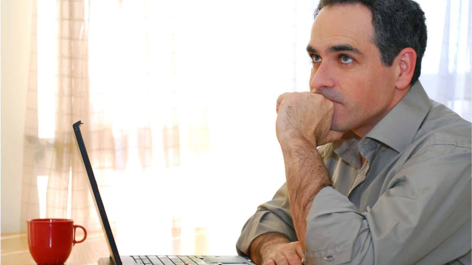 Man sitting thinking at a desk and looking into his computer