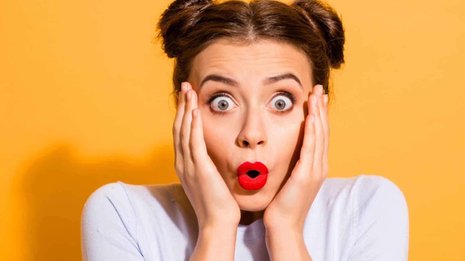 Shocked woman with red lipstick isolated in yellow background