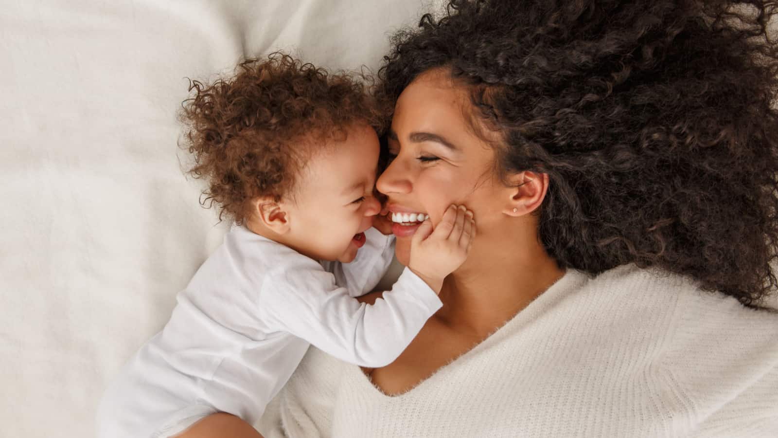 mom and baby on bed laughing