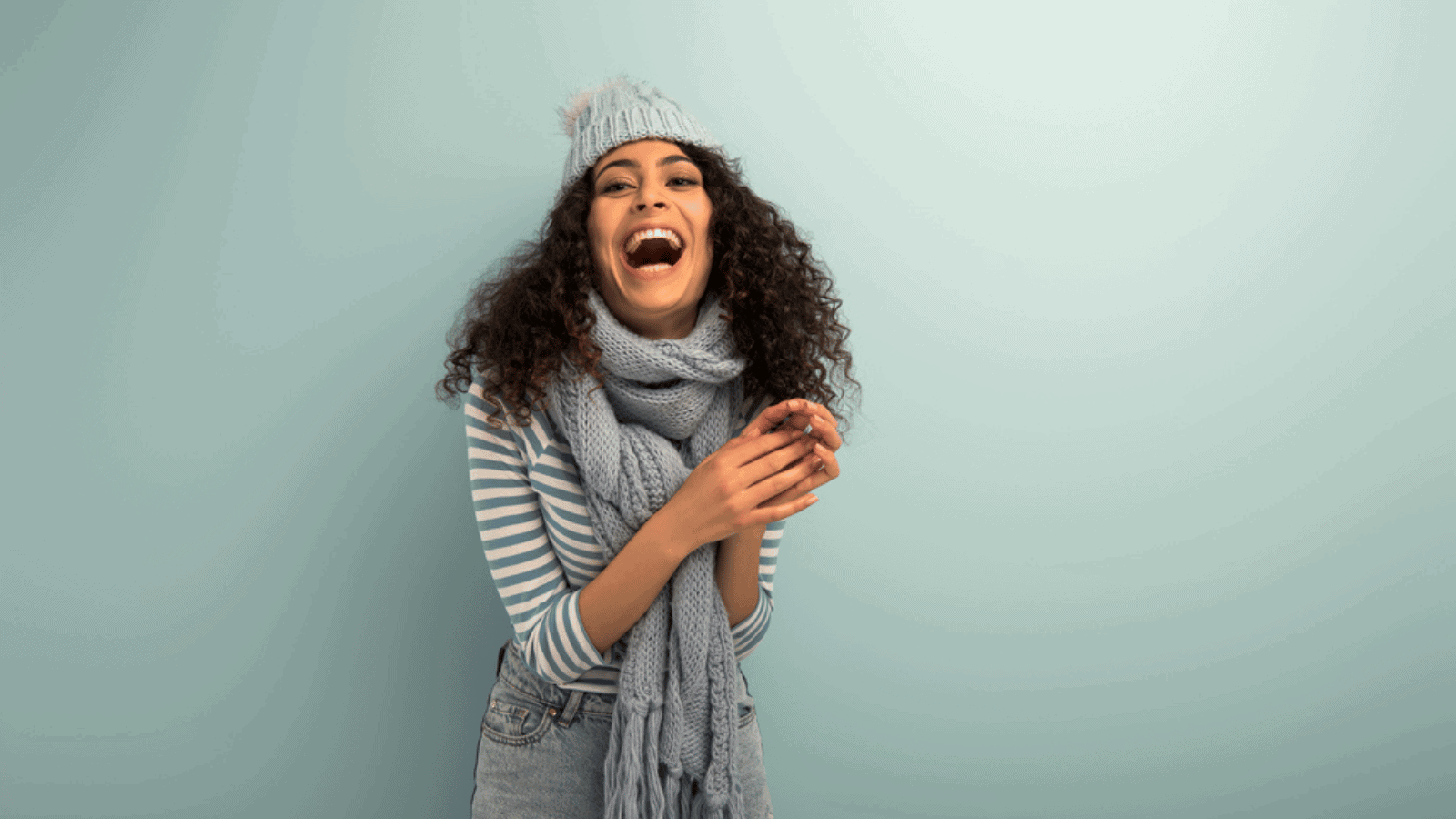 woman laughing winter hat and sweater blue