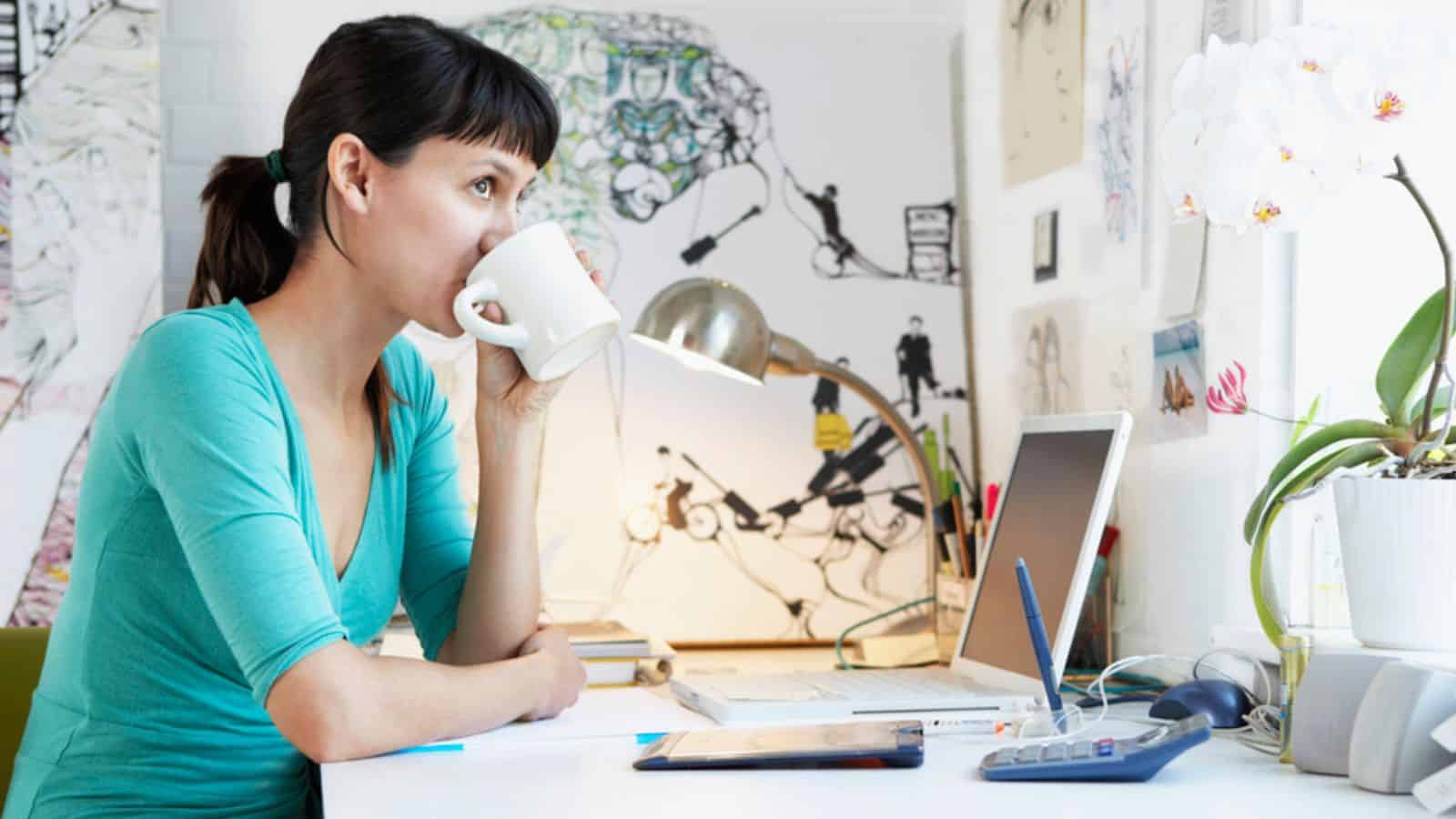 Woman working at a desk while drinking coffee