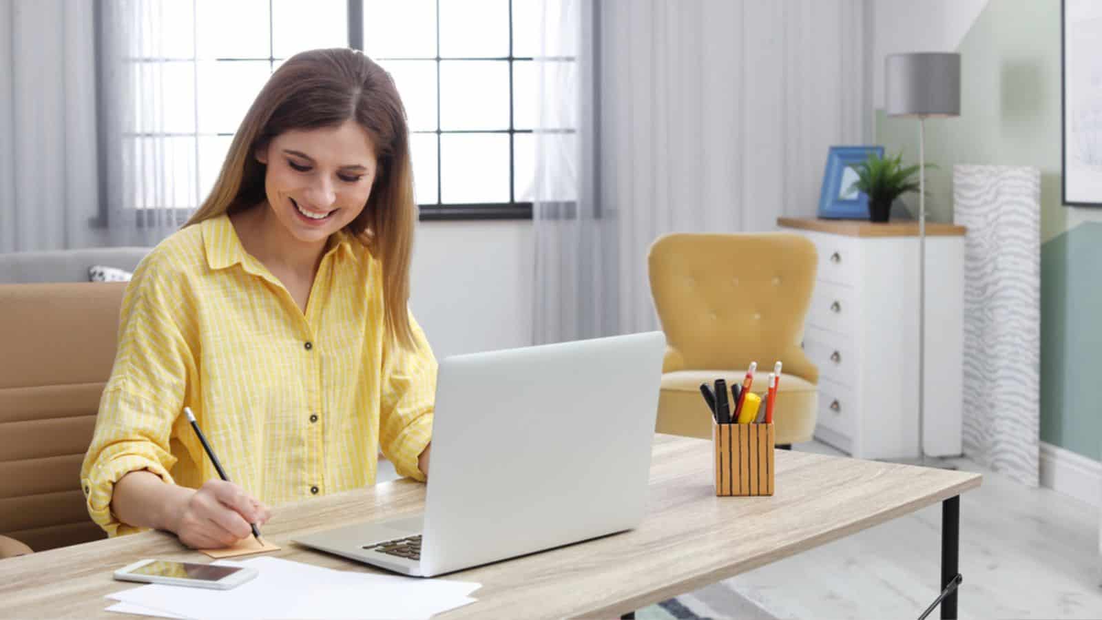 Young woman working with laptop at desk in work from home