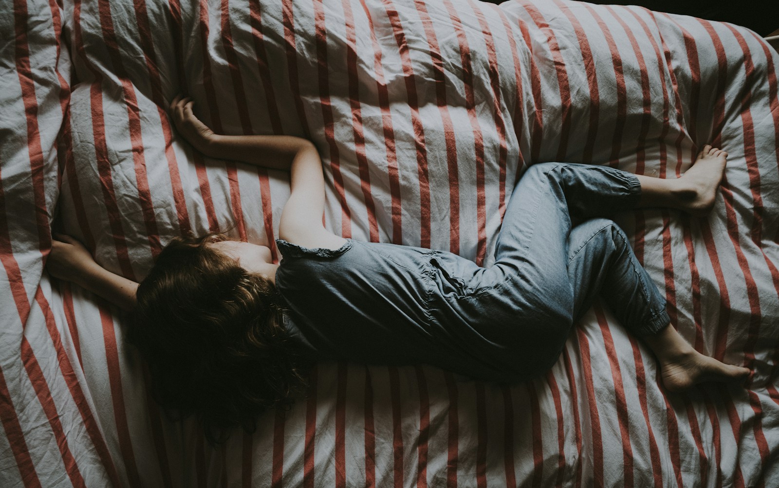 kid sleeping on red and gray bed; melatonin gummies for kids