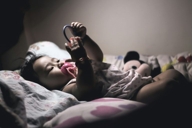girl in pink shirt lying on bed; overnight wakings