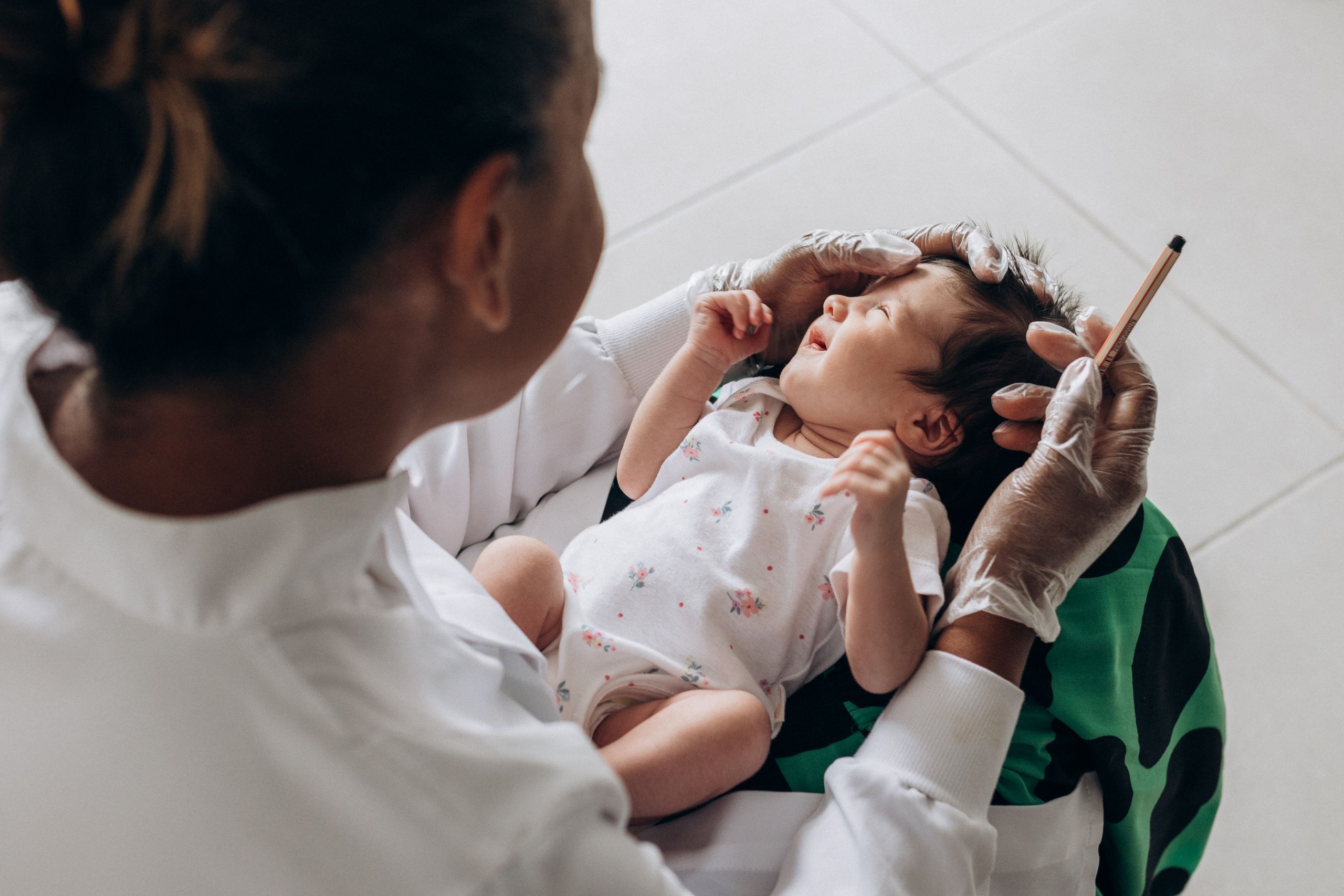 A medical professional examines a newborn baby indoors, highlighting healthcare and care; rash on baby's face