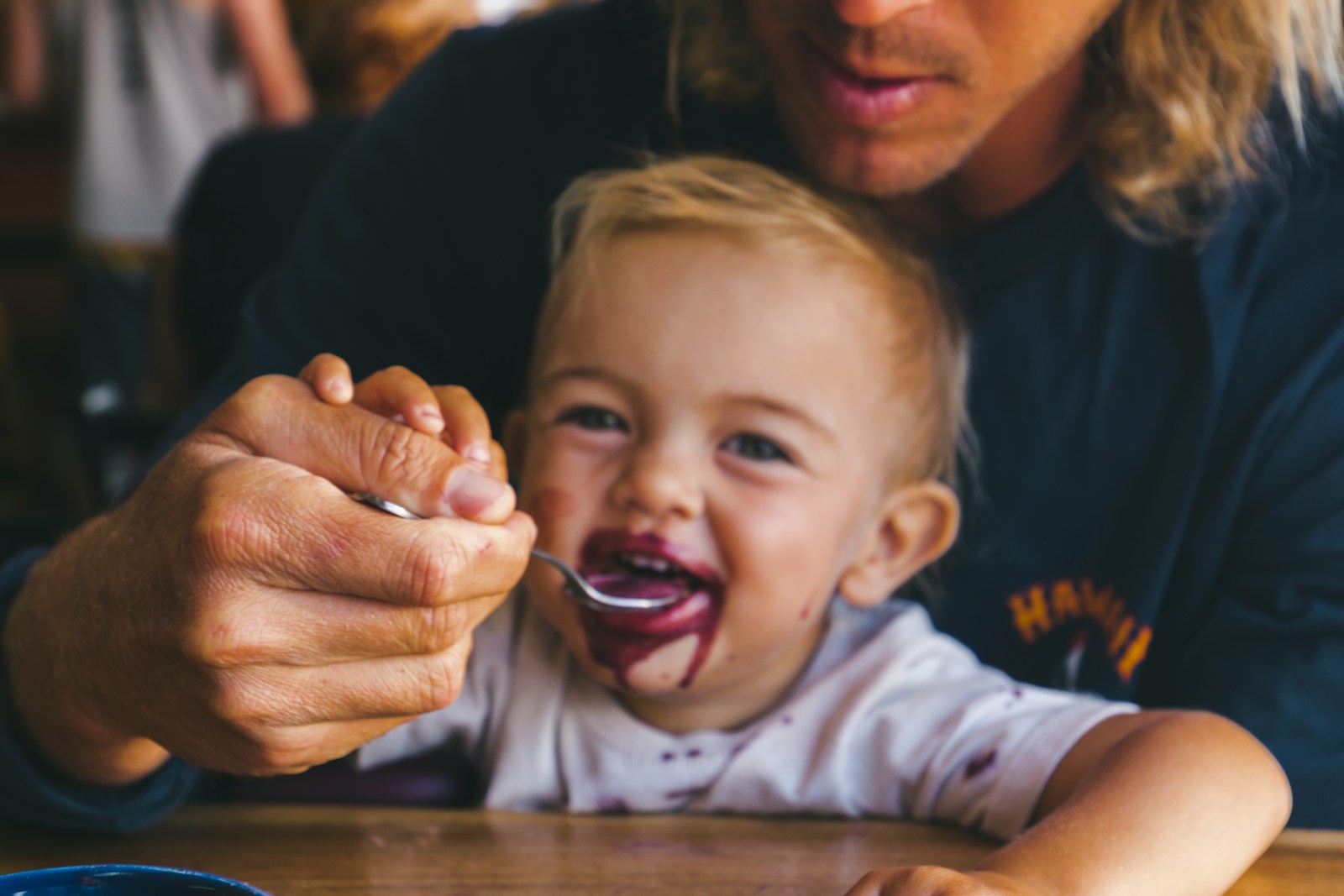 a woman feeding a child a spoon of food; when to introduce allergens