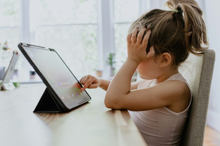 girl in white tank top using black tablet computer; screen-free fall bucket list