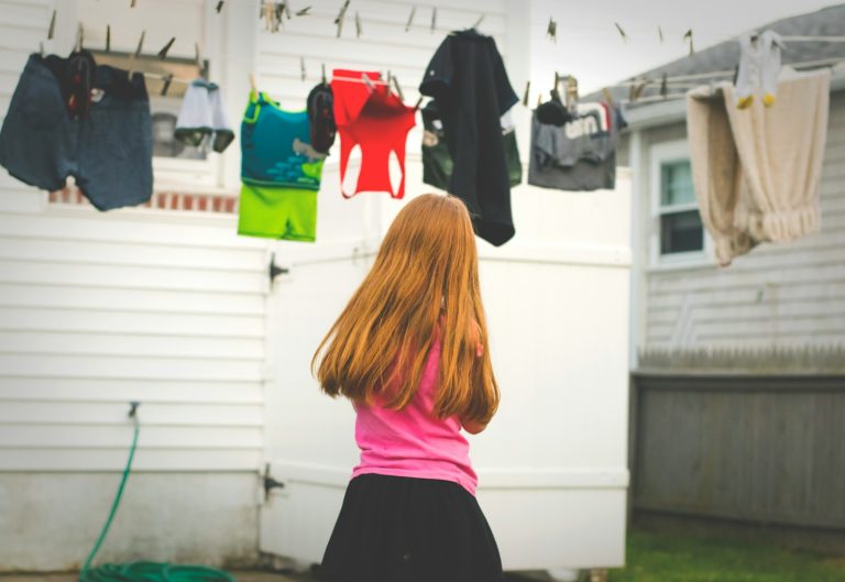 girl standing under clothes on airer at daytime; daily routine chart
