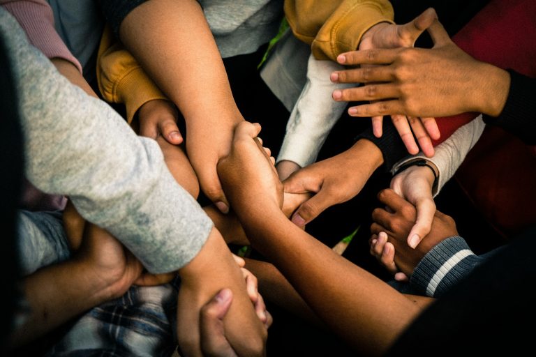 a group of people holding hands; village parenting trend
