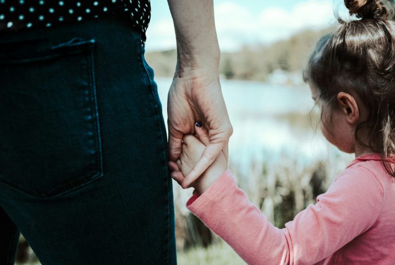 girl in pink jacket holding her hair; mom guilt