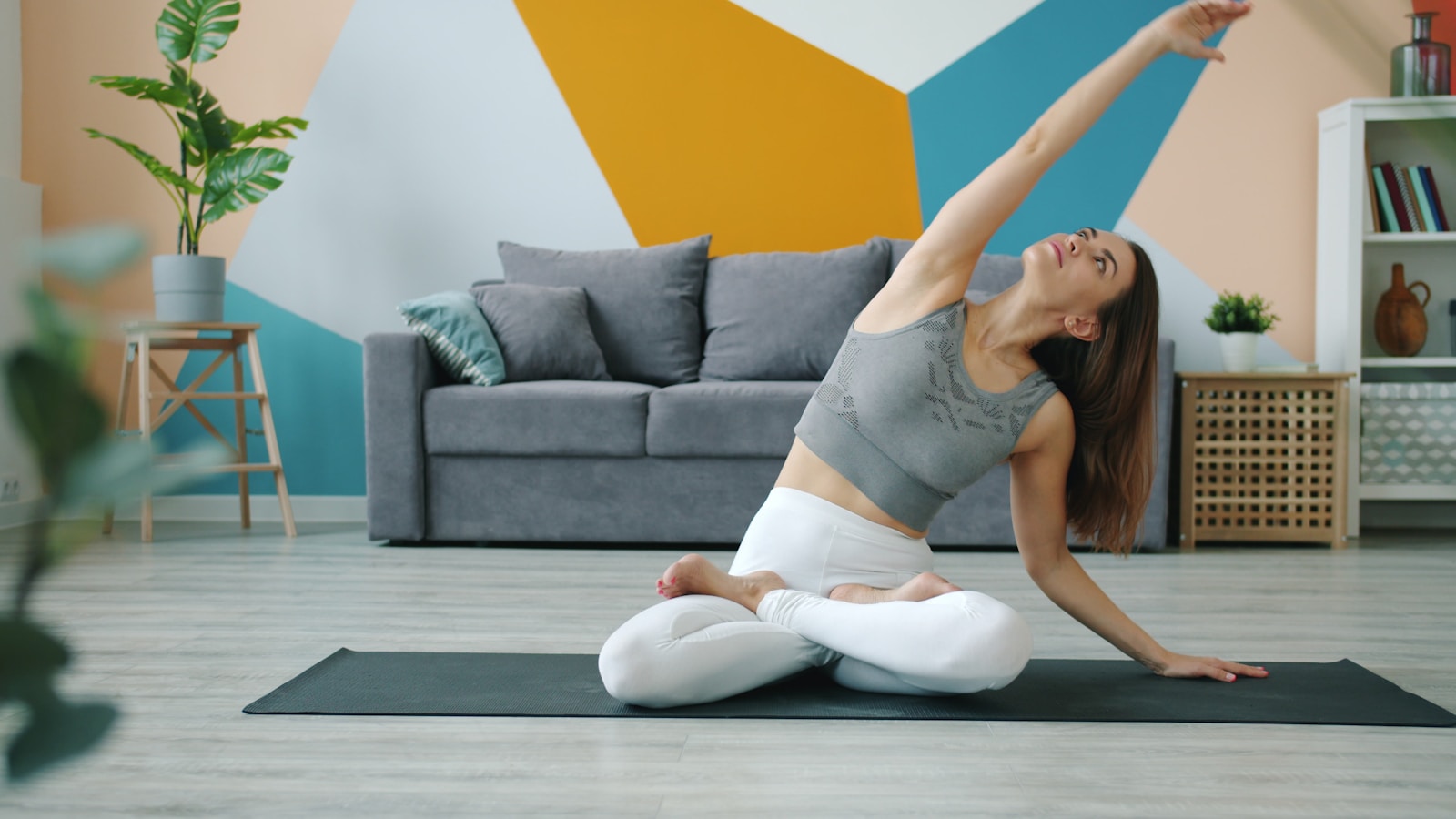 Woman practicing yoga on a mat in a living room.; pelvic floor recovery