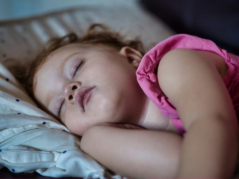 a little girl sleeping on a bed with her eyes closed; afternoon nap