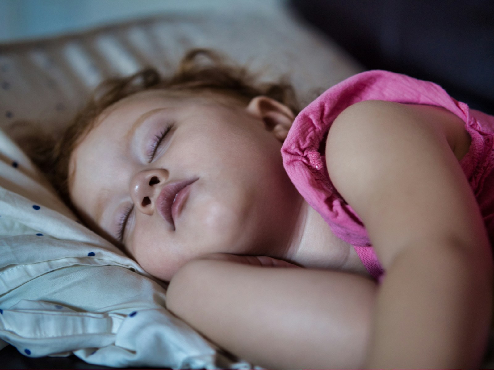 a little girl sleeping on a bed with her eyes closed; afternoon nap