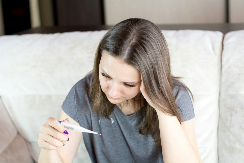 a woman sitting on a couch holding a pen and paper; fever in babies