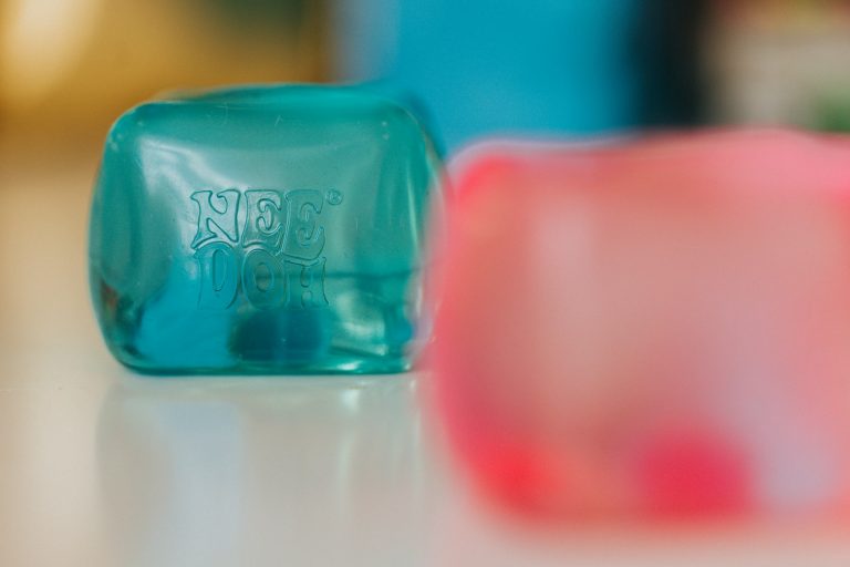 Teal cube with "not yet" text, blurred pink cube nearby; squishy toys