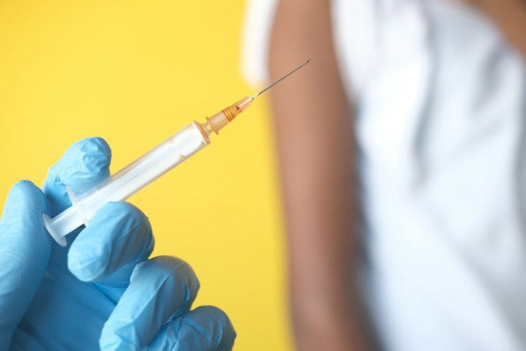 a person in blue gloves holding a syquet; vaccine schedules