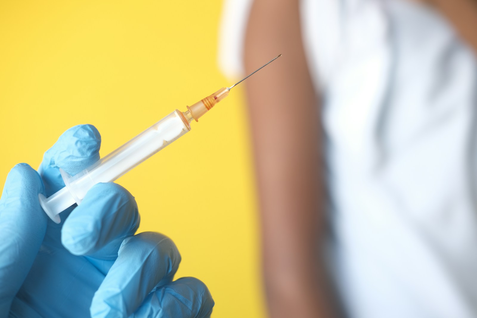 a person in blue gloves holding a syquet; vaccine schedules