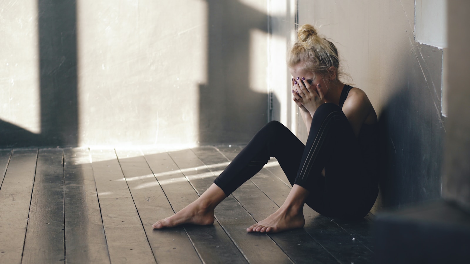 Woman sitting on floor, covering face with hands.; baby blues vs postpartum depression