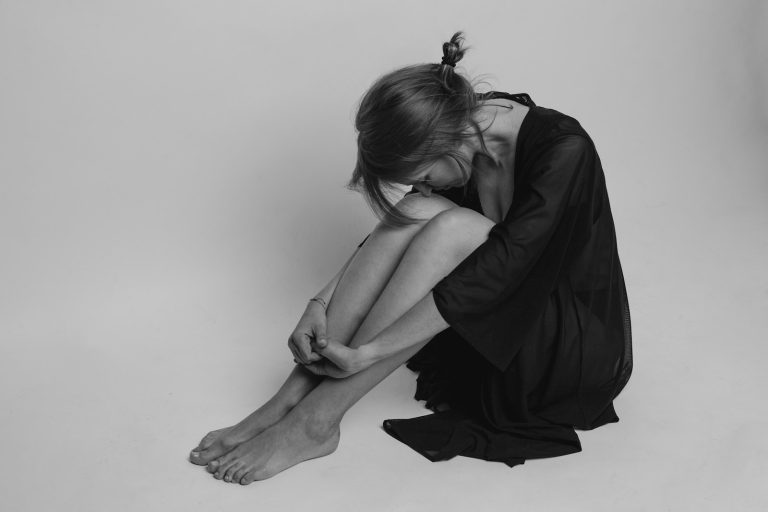woman in black dress sitting on floor; postpartum psychosis