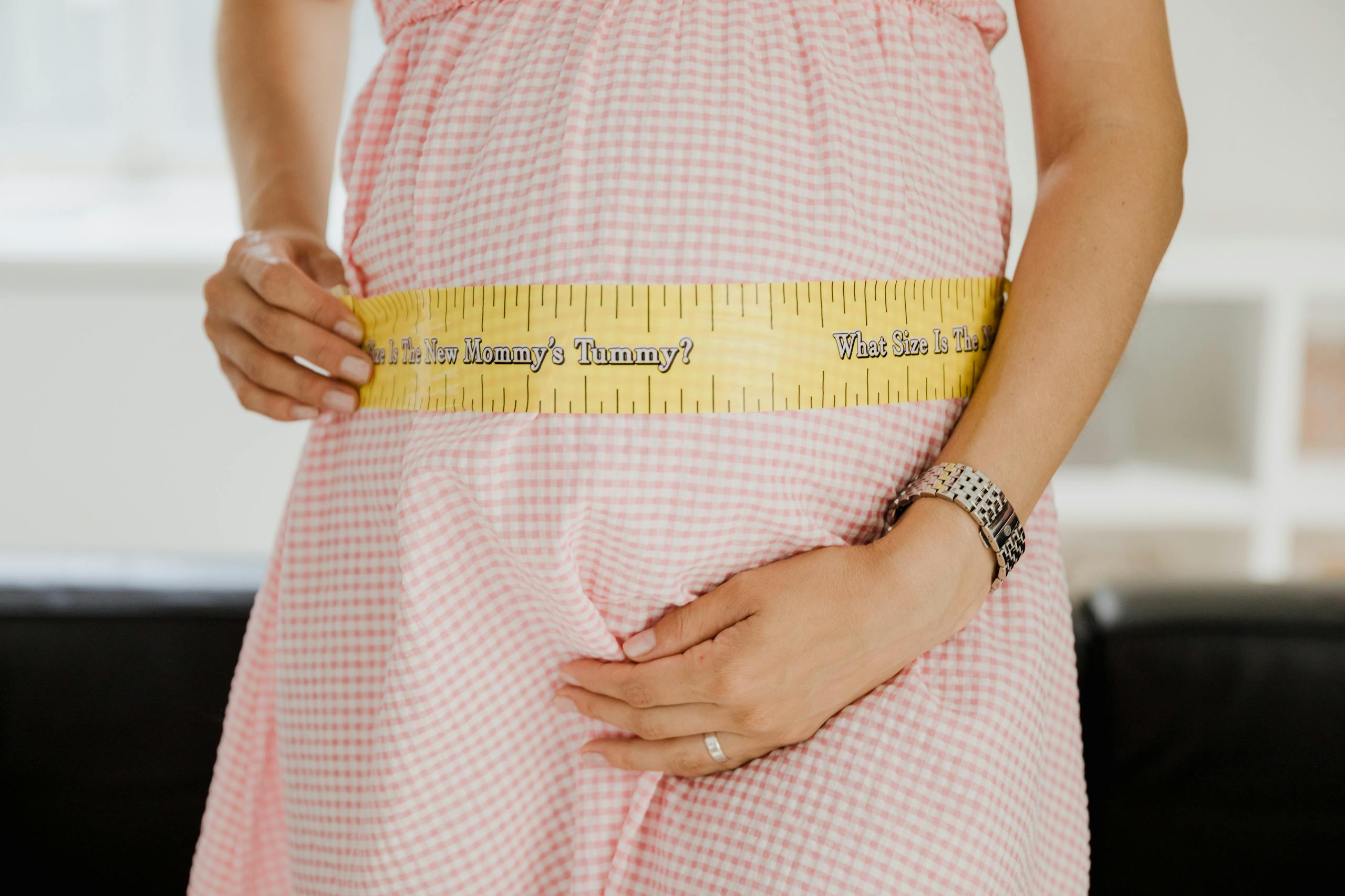 Pregnant woman's belly with a tape measure in a cozy indoor setting, symbolizing joy.; fourth trimester