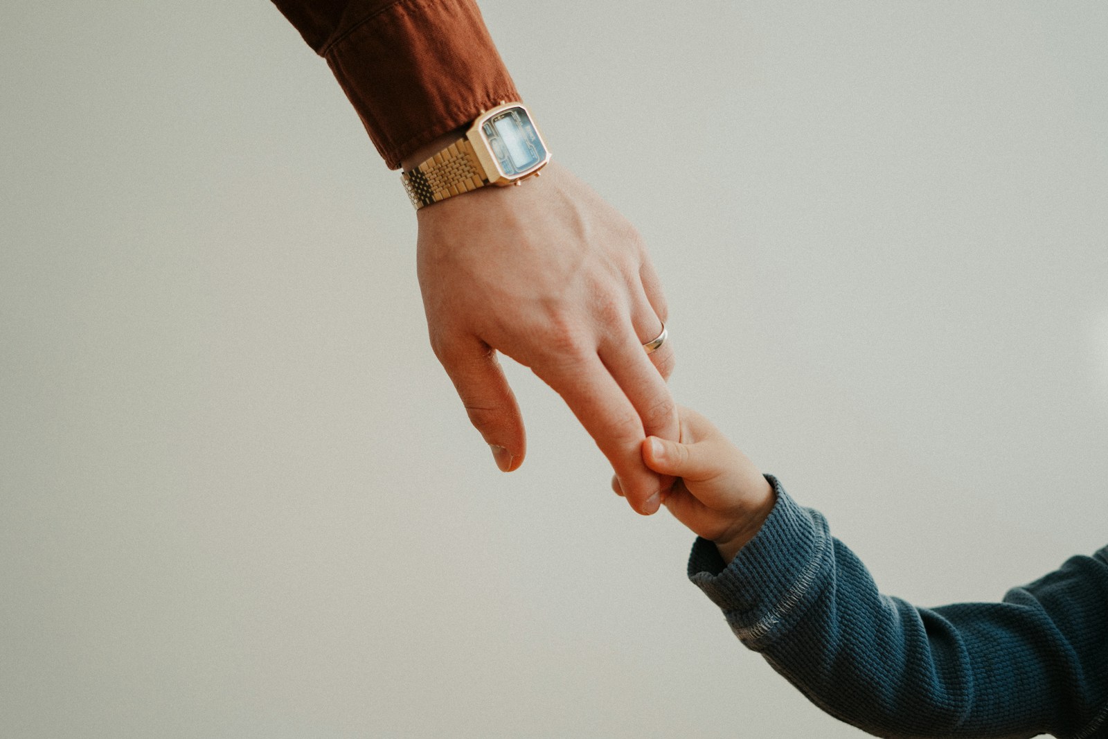 a person holding the hand of a child; gentle parenting backlash