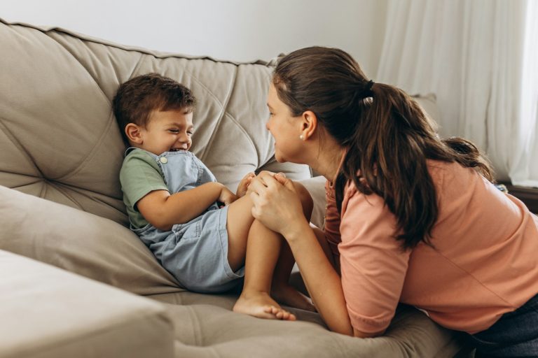 a woman sitting on top of a couch next to a little boy; gentle parenting