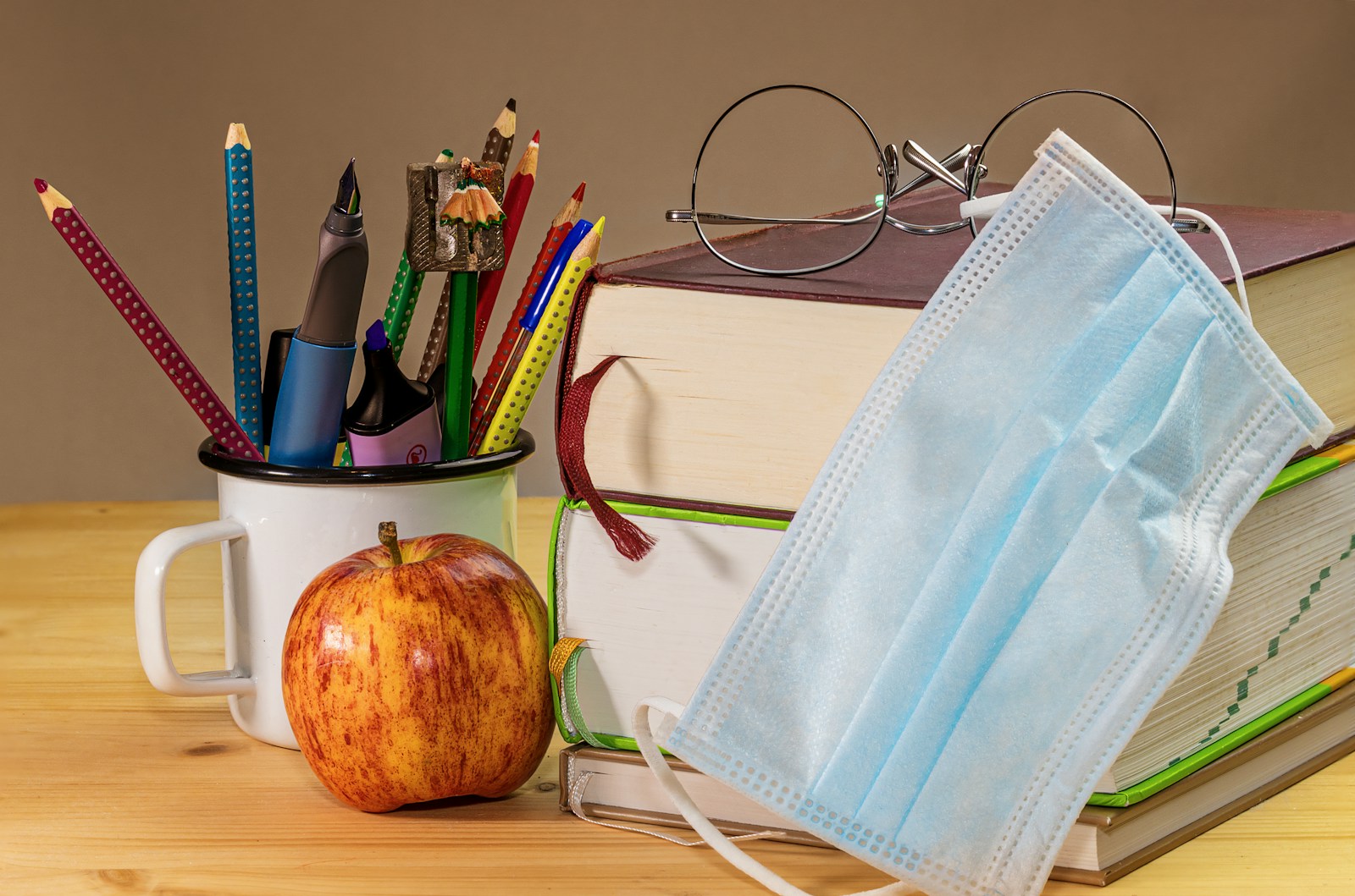 an apple, a book, a face mask, and a pair of glasses are; back to school illness