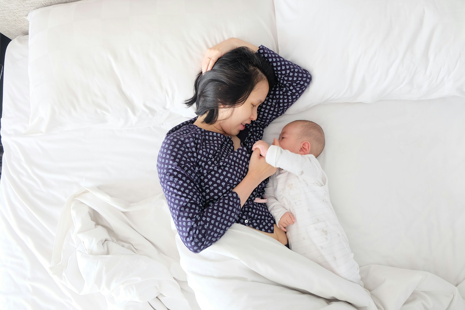 woman and baby lying on bed; sleep regression
