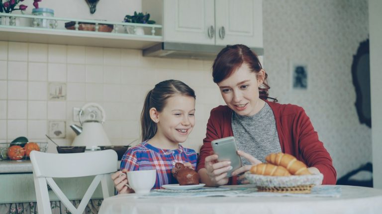 A mother and daughter share a phone together; AI-enabled parenting