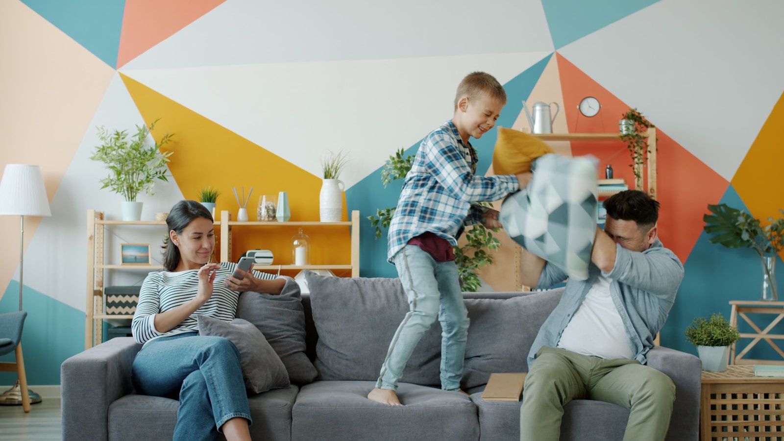 Family having a pillow fight on the couch; split shift parenting